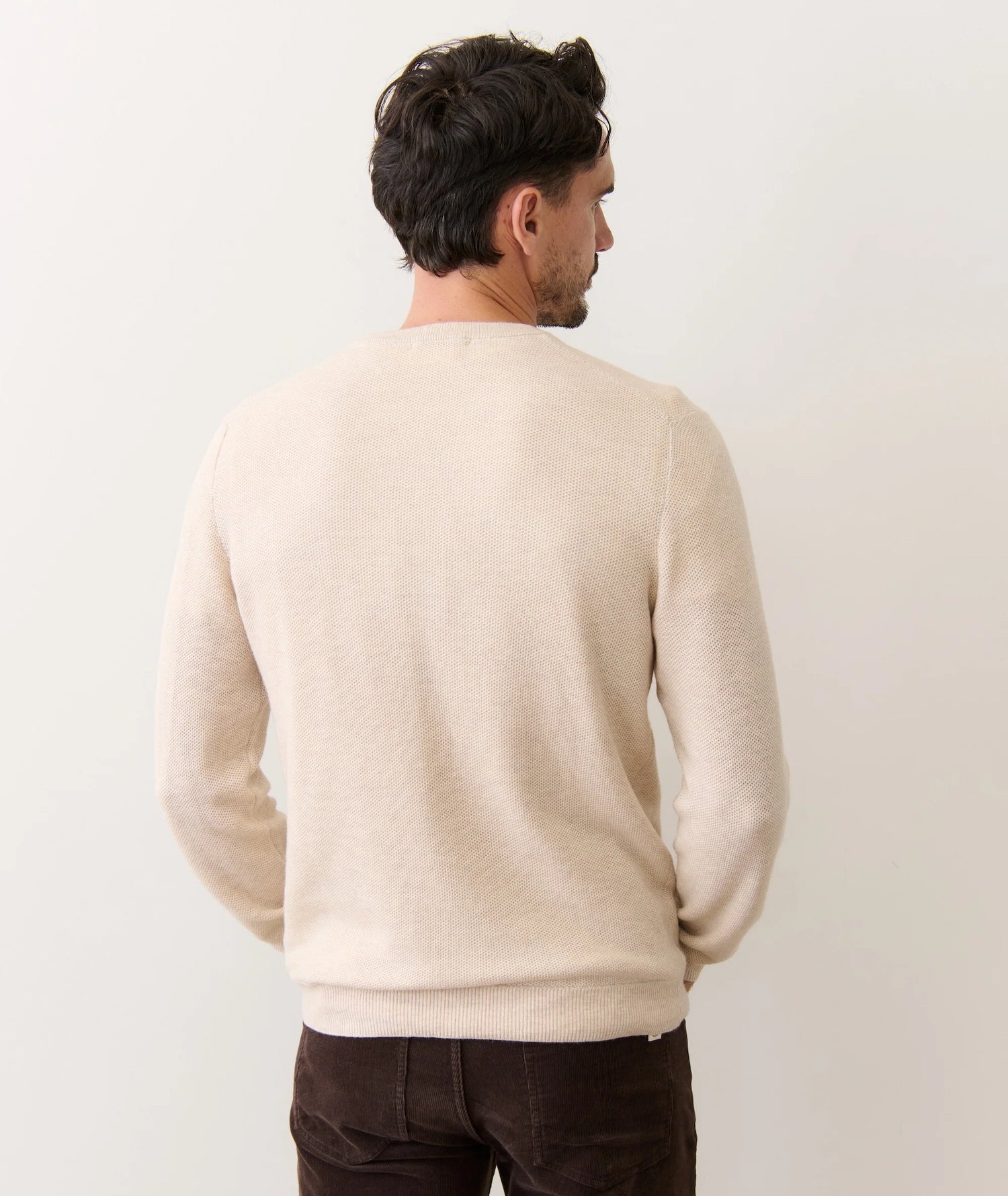Man wearing a beige sweater against a plain background