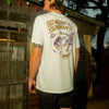 Person wearing a white t-shirt with text and graphics, standing outdoors.