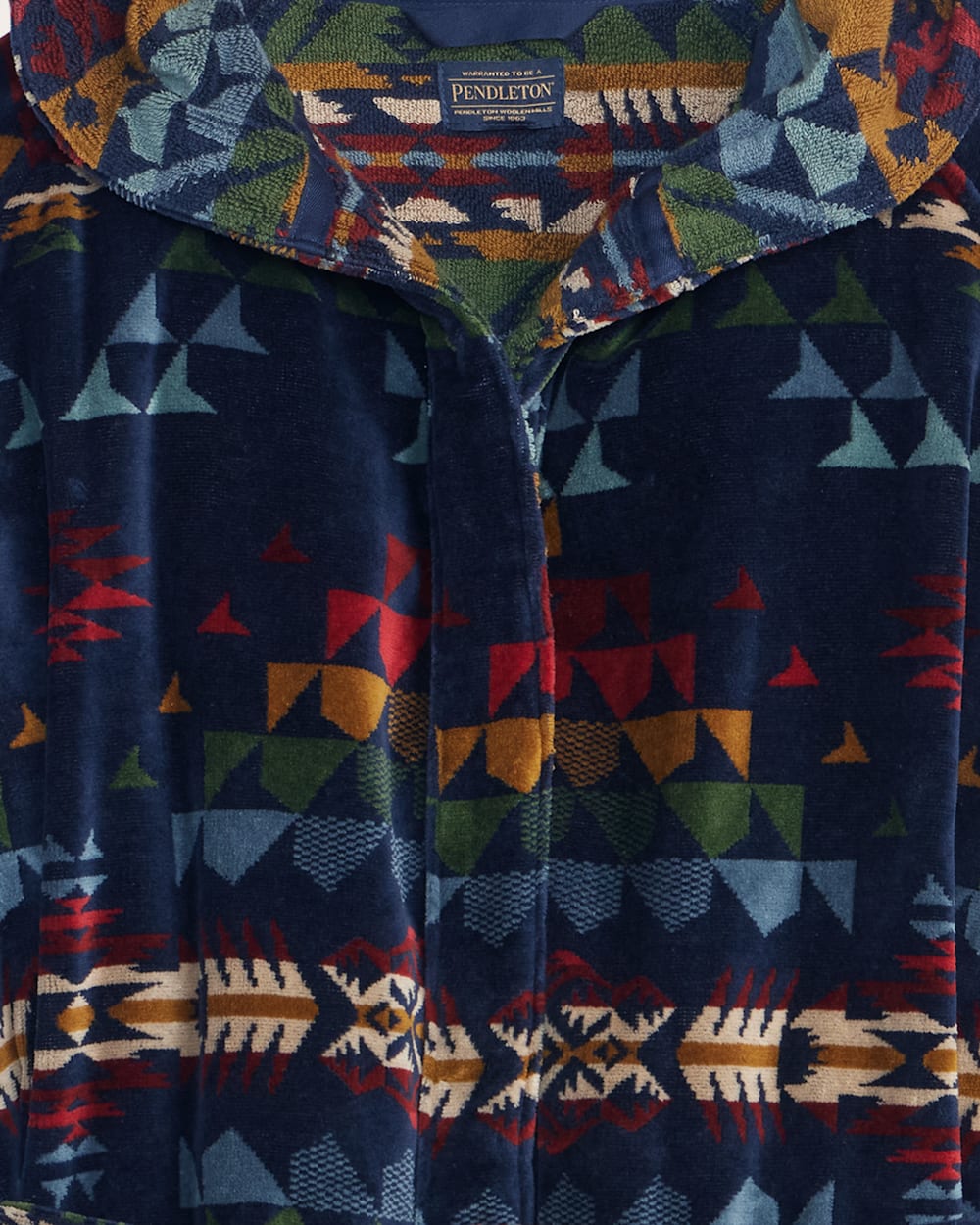 Close-up of a colorful patterned jacket with geometric designs on a dark blue background.