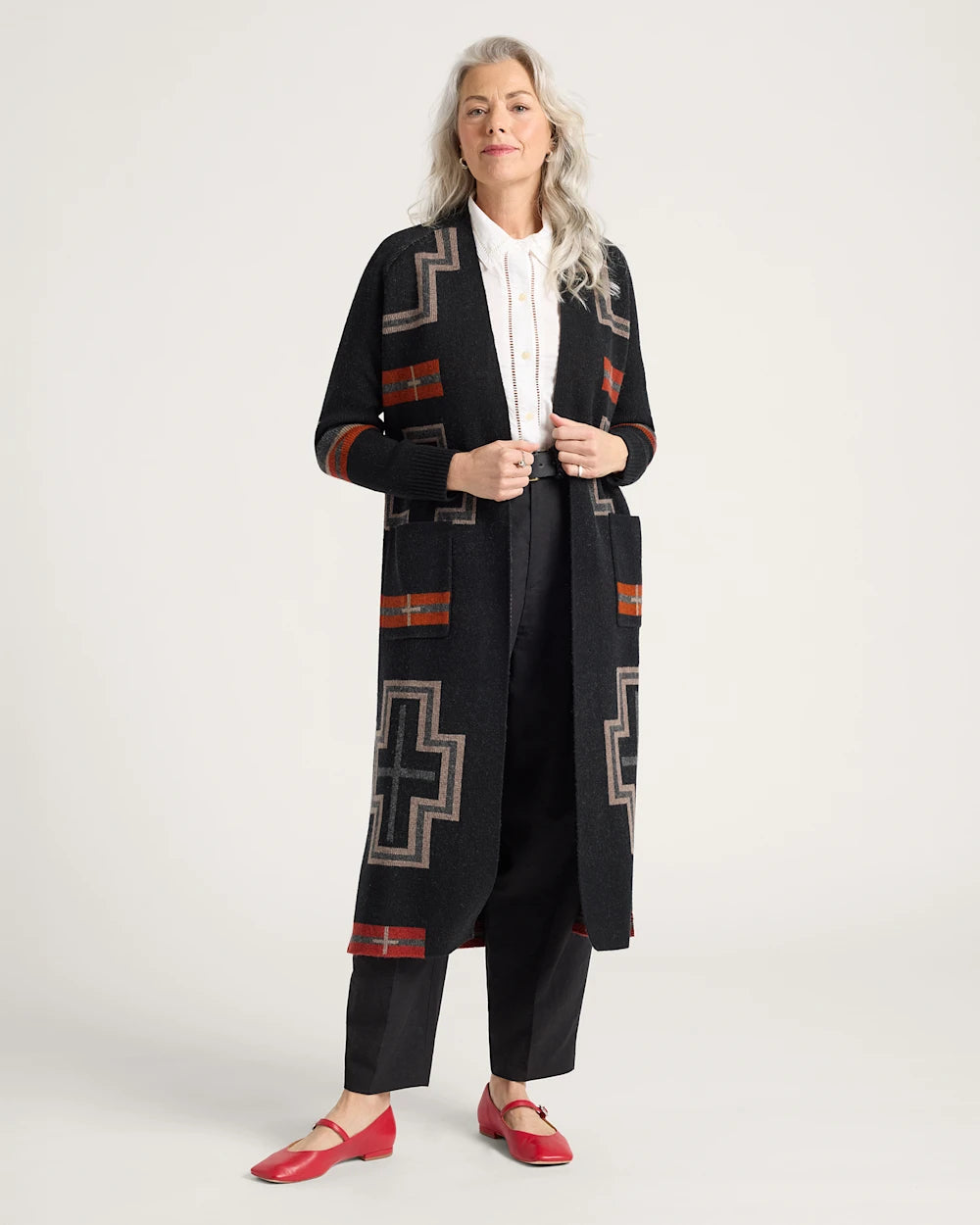Woman wearing a long black cardigan with geometric patterns on a white background