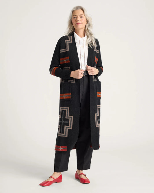 Woman wearing a long black cardigan with geometric patterns on a white background