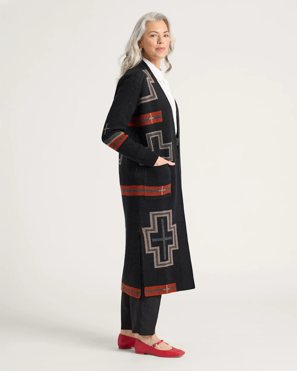 Woman wearing a long black coat with geometric patterns on a white background