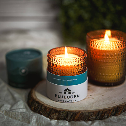 Candle with Bluecorn Aromática branding on a wooden surface