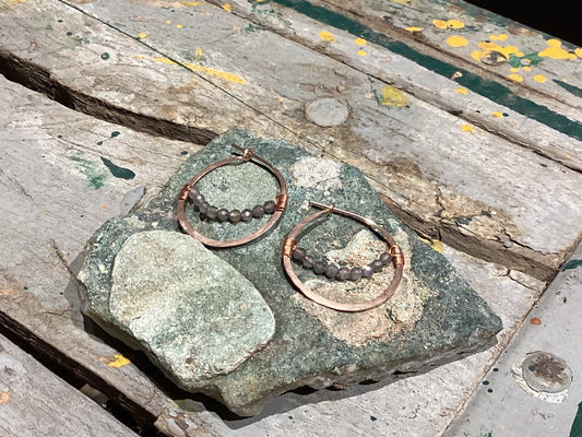 Pair of hoop earrings with beads on a stone surface
