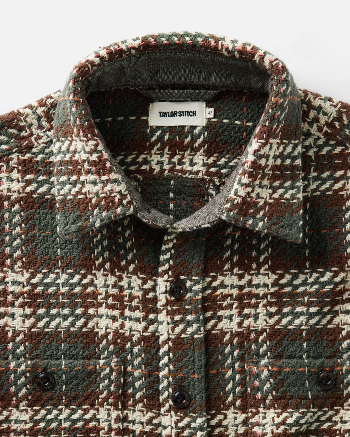 A close-up of a Taylor Stitch button-down shirt featuring a textured houndstooth pattern in brown, olive green, and cream.