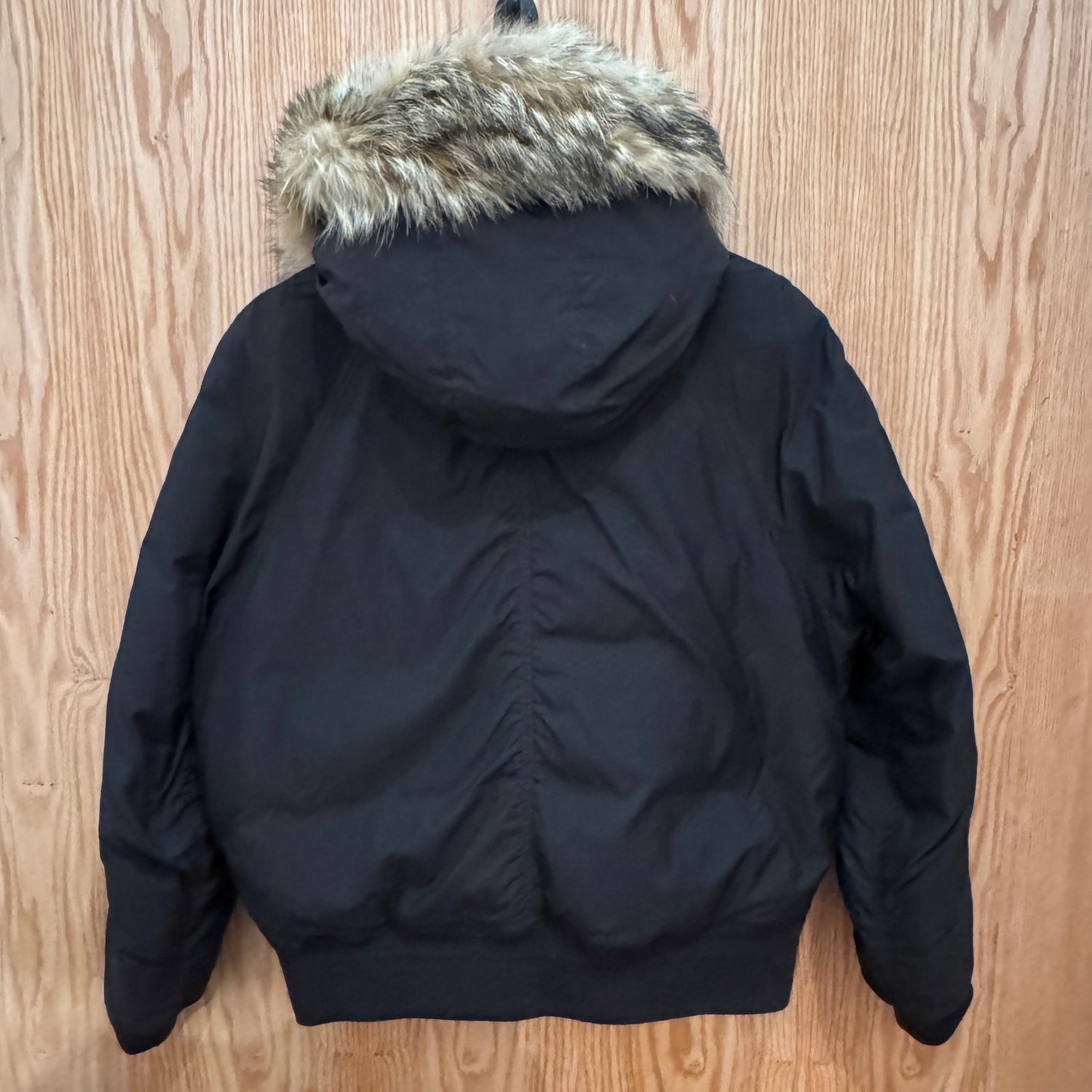 Black jacket with fur hood on a wooden surface