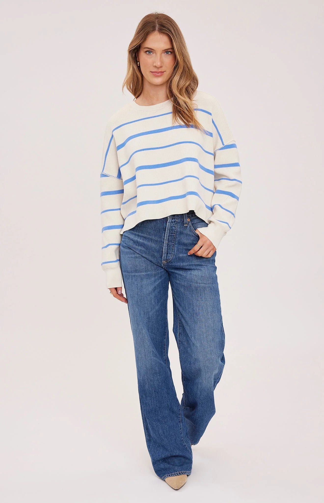 Woman wearing a striped sweater and blue jeans on a white background