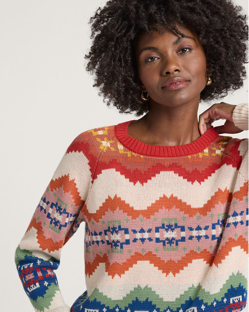 Woman wearing a colorful patterned sweater against a plain background