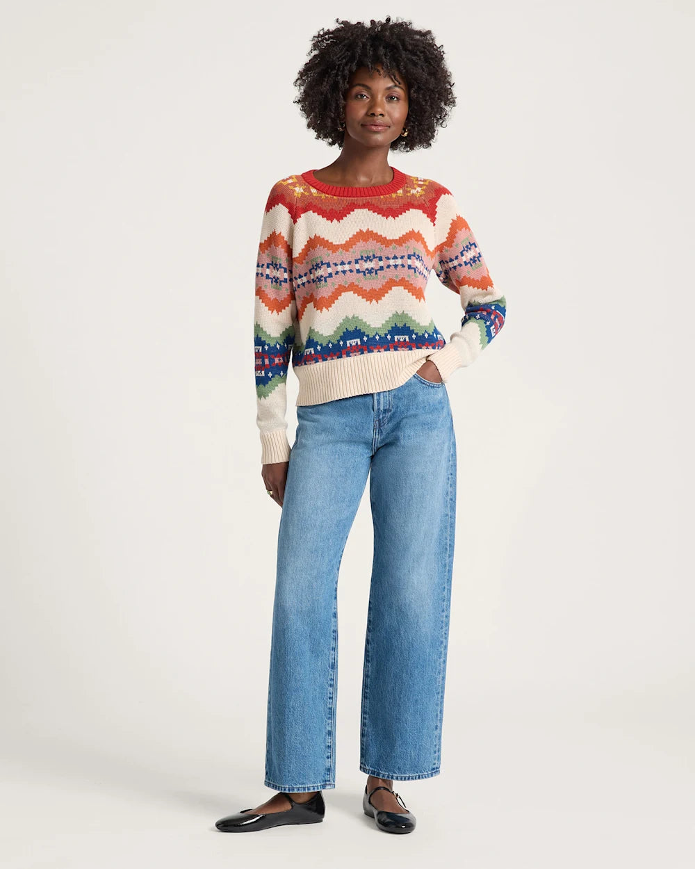 Woman wearing a colorful sweater and blue jeans on a white background