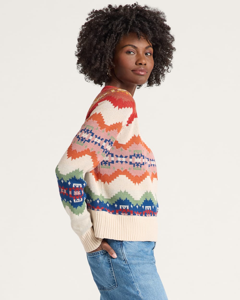 Person wearing a colorful patterned sweater on a plain background