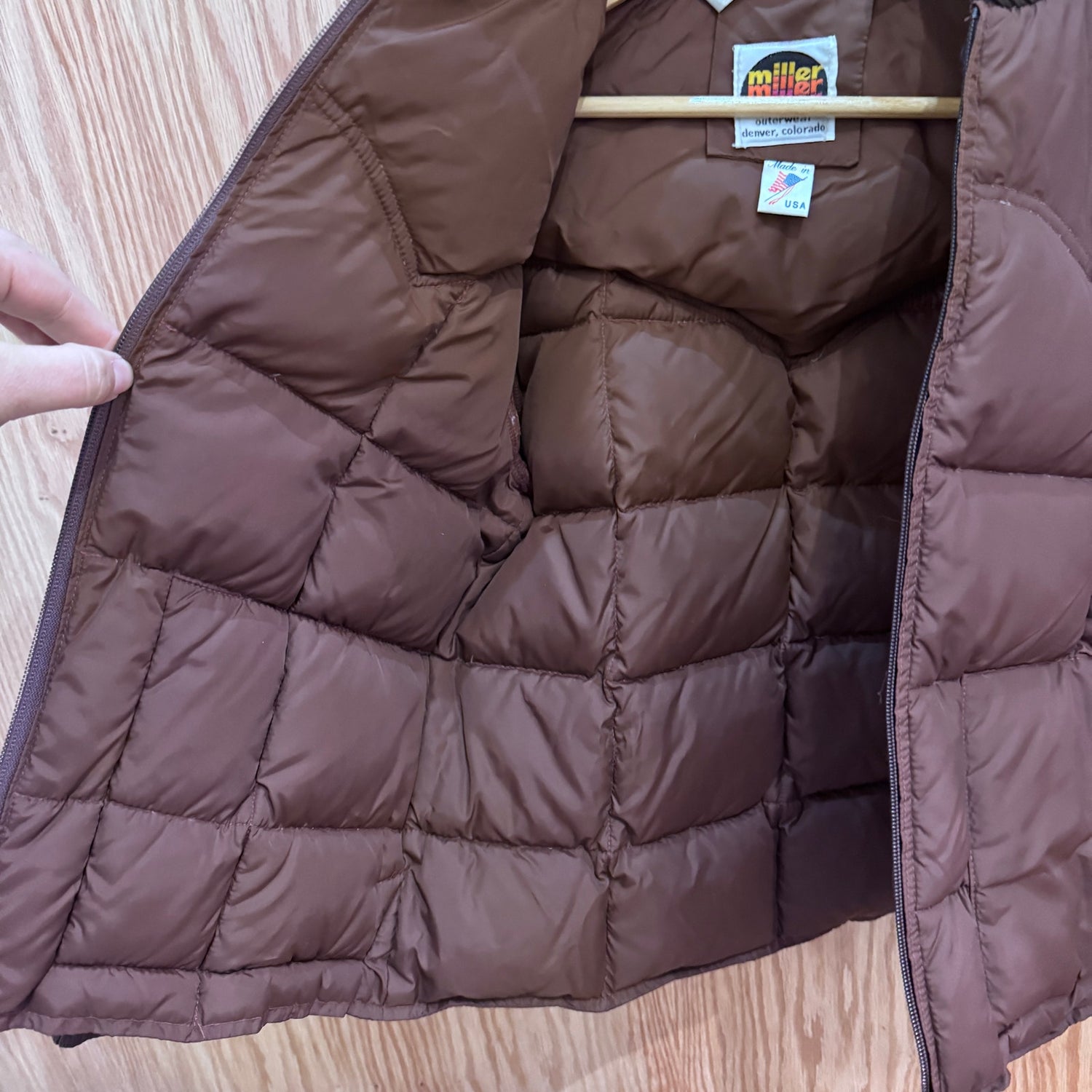 Brown quilted jacket with a visible brand label on a wooden surface