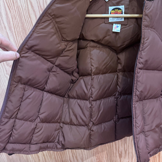 Brown quilted jacket with a visible brand label on a wooden surface