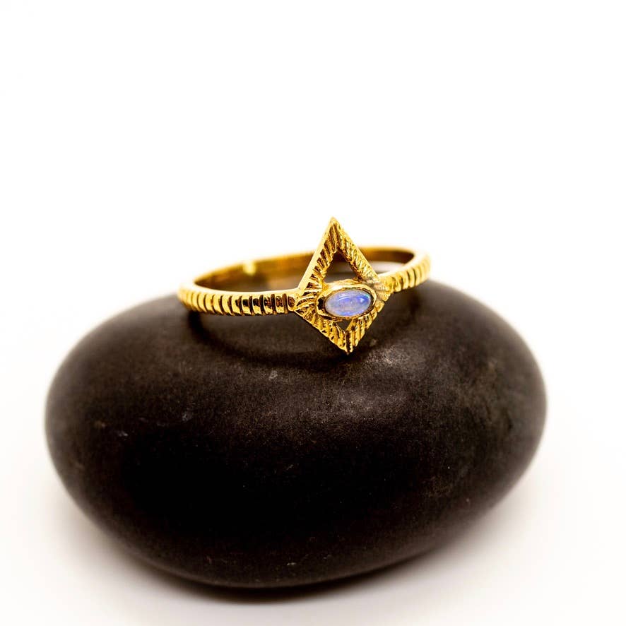Gold ring with a blue stone on a black stone surface