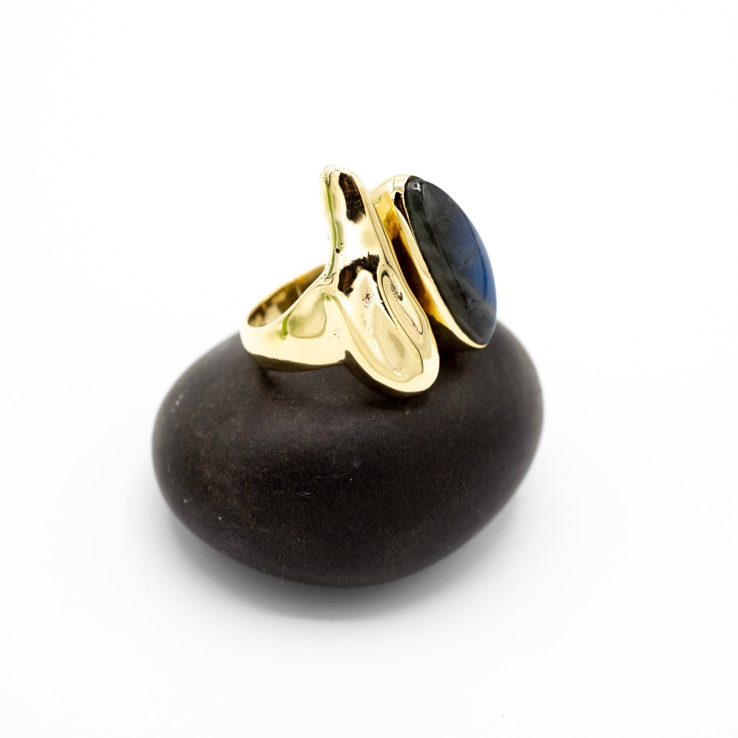 Gold ring with a black stone on a black stone base against a white background