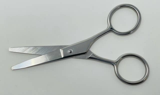 Pair of silver scissors on a light gray background
