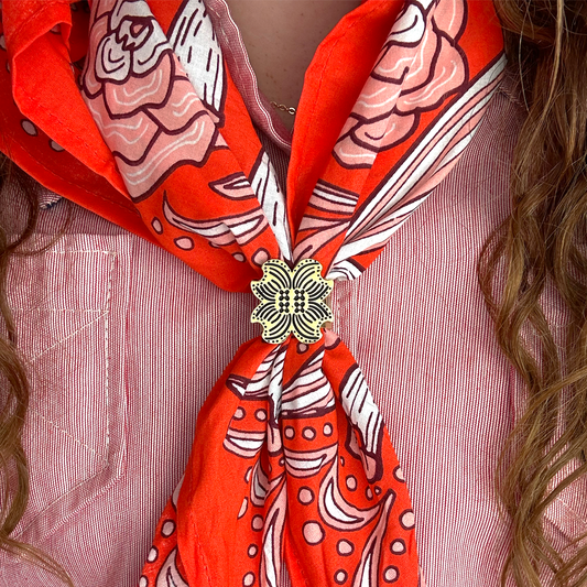 Red patterned scarf with a decorative brooch on a pink shirt