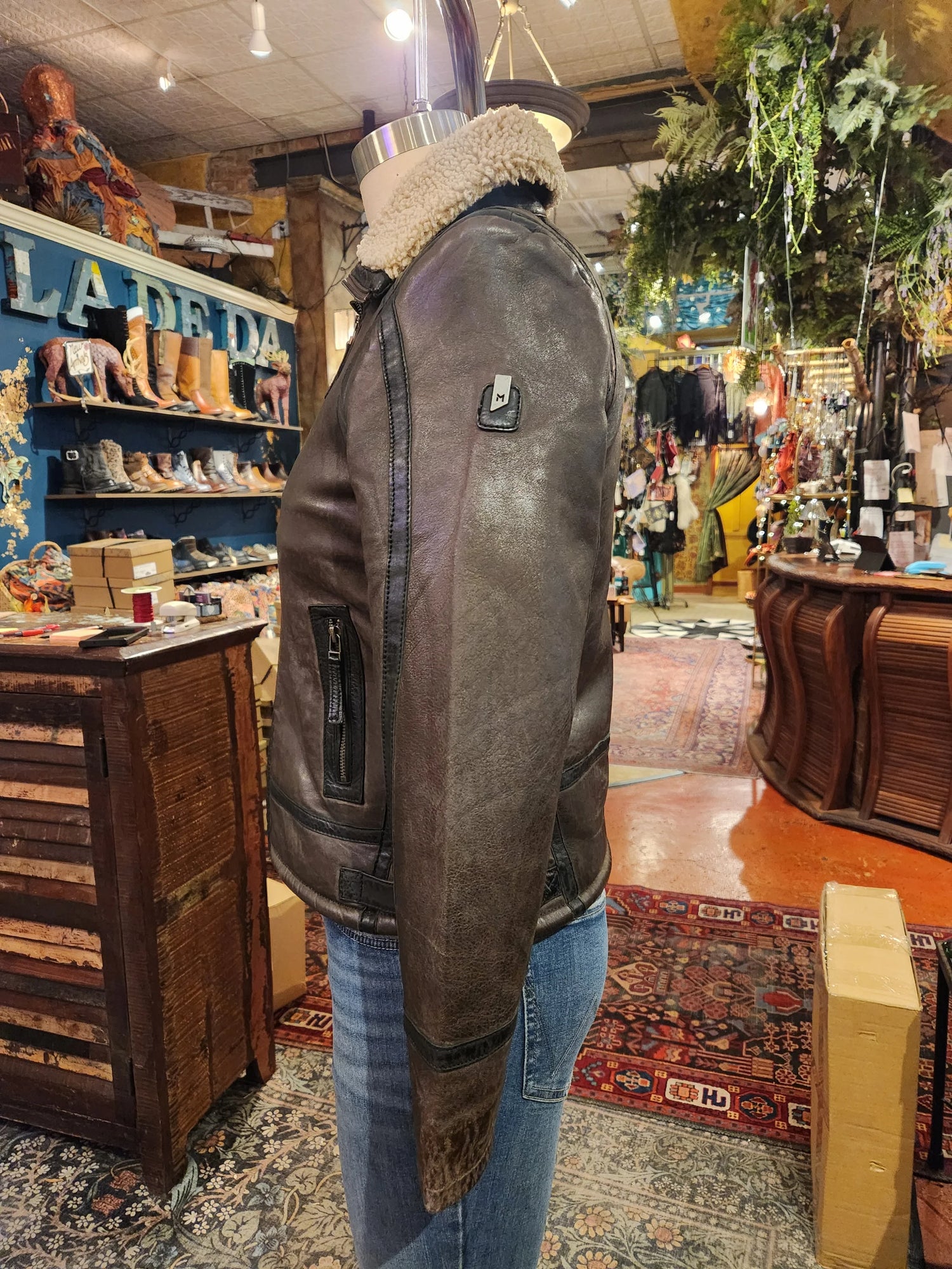 Person wearing a brown leather jacket with fur lining in a store setting