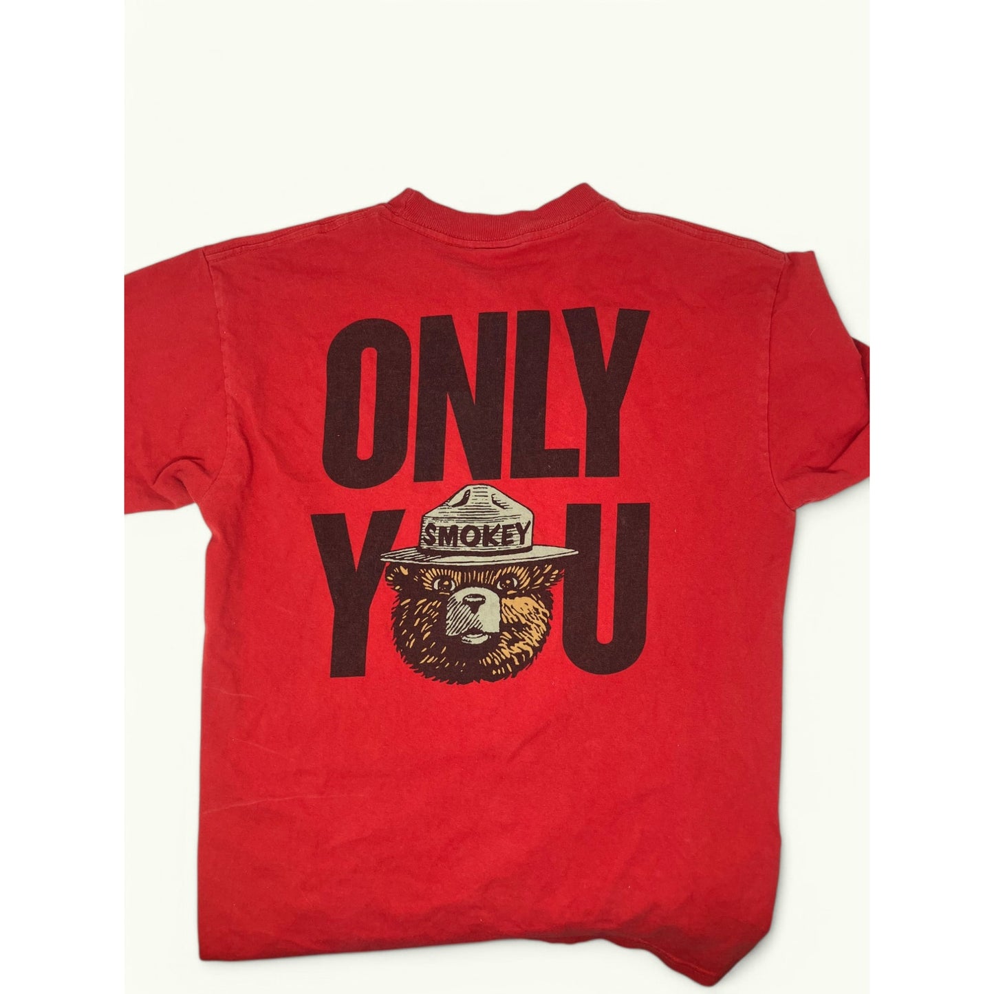 A red short-sleeve t-shirt laid flat, featuring a large black graphic on the back that reads 'ONLY YOU' with a Smokey Bear illustration integrated into the lettering.