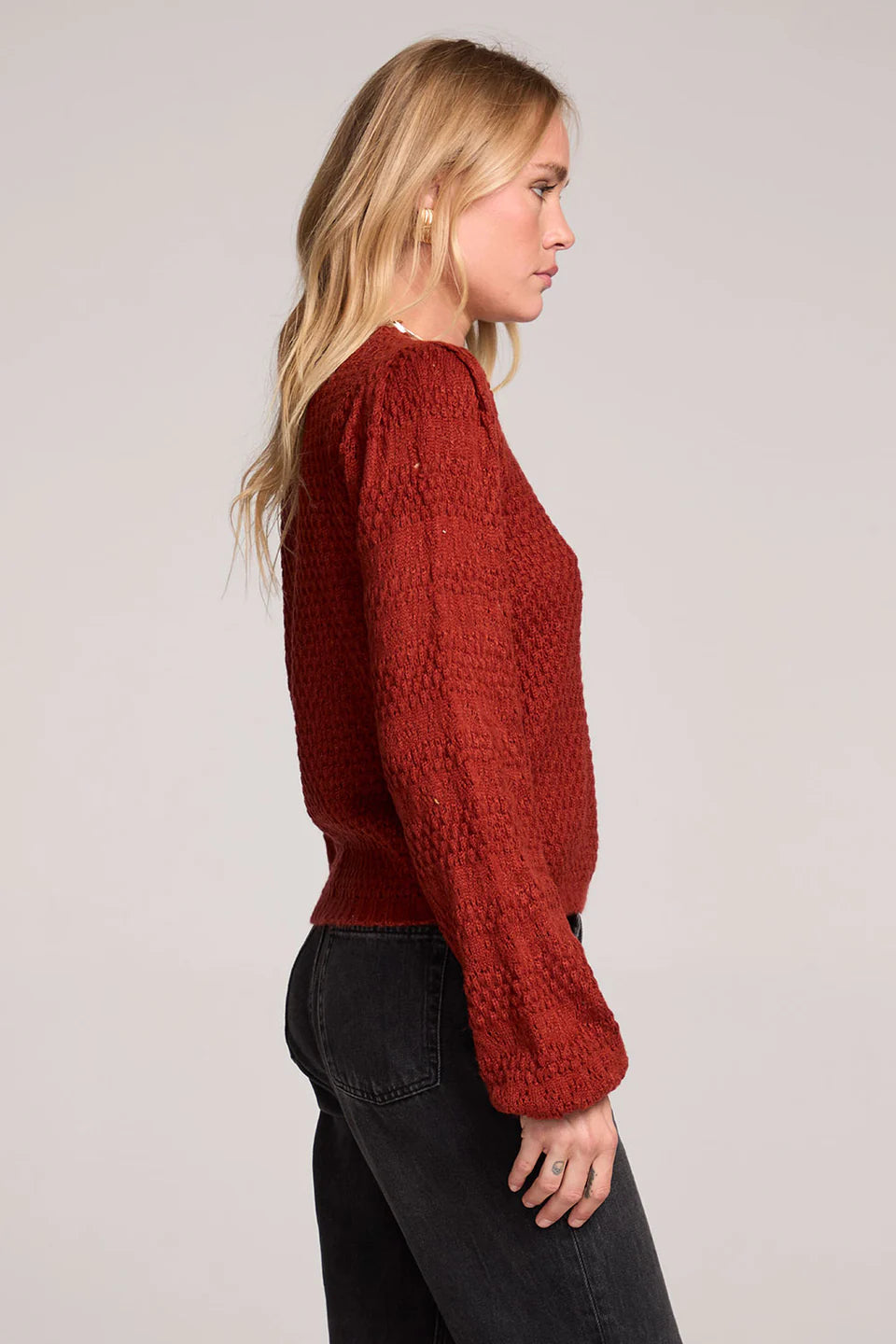 Woman wearing a red knitted sweater against a plain background