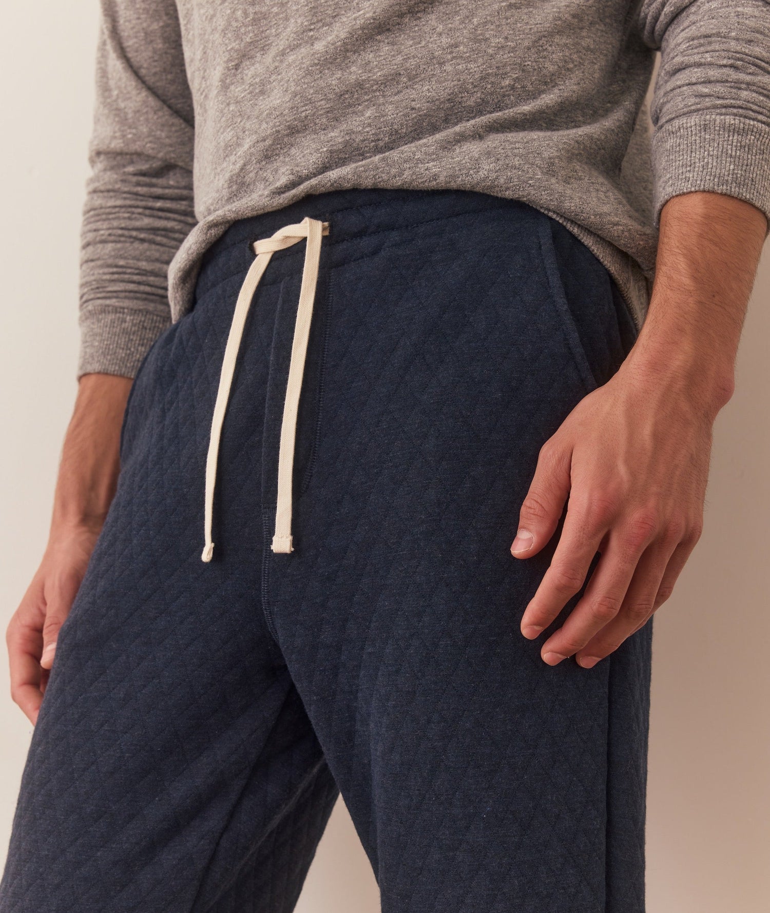 Person wearing navy jogger pants with a beige drawstring and gray top on a neutral background