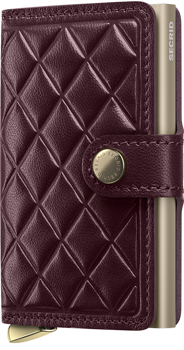 Quilted leather wallet with gold accents and 'Secrid' branding on a dark background