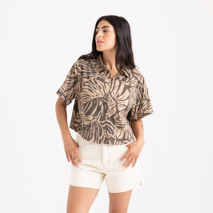 Woman wearing a patterned shirt and white shorts on a white background