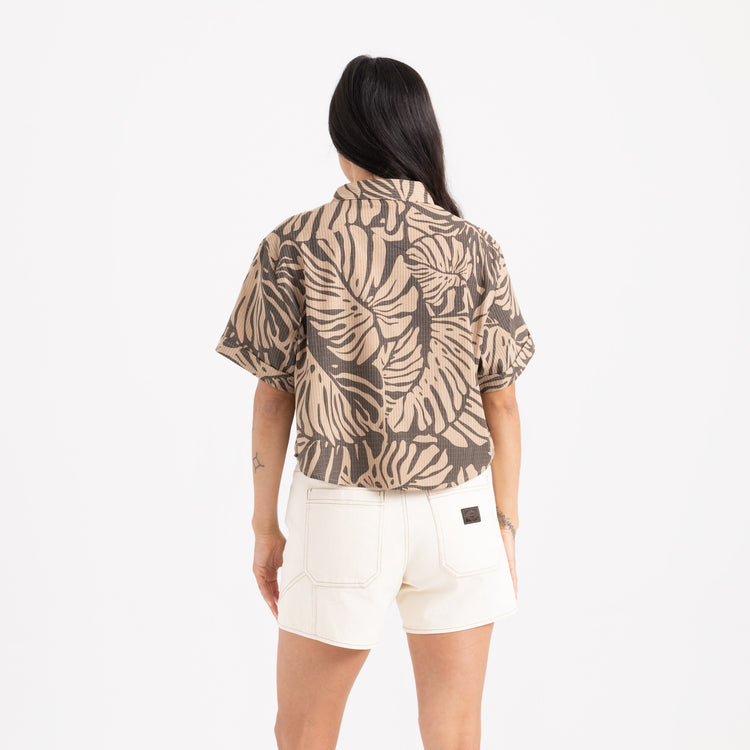 Person wearing a patterned shirt and white shorts on a white background