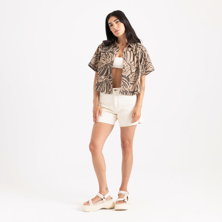 Woman wearing a patterned shirt and white shorts on a white background