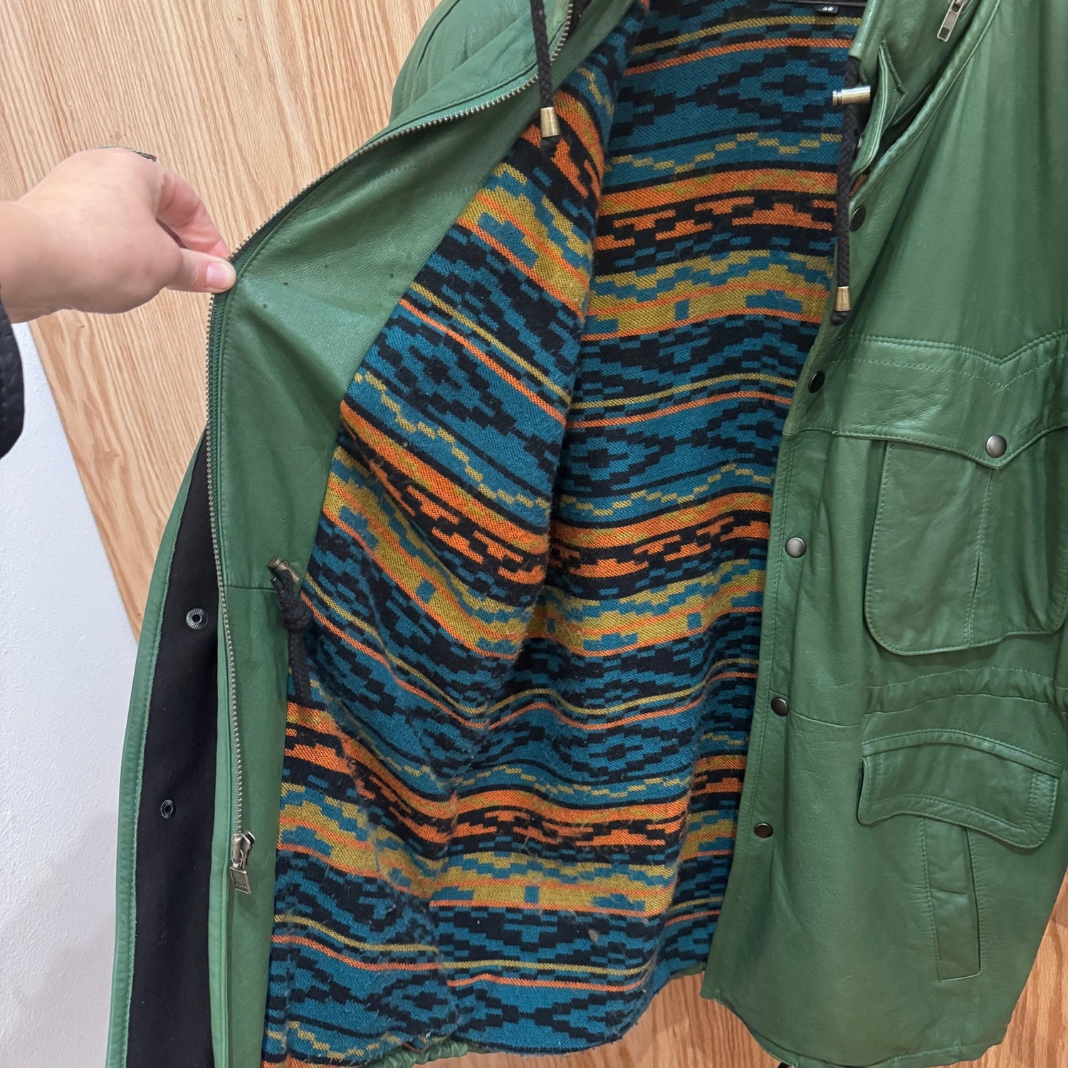 Green jacket with a colorful patterned lining on a wooden surface