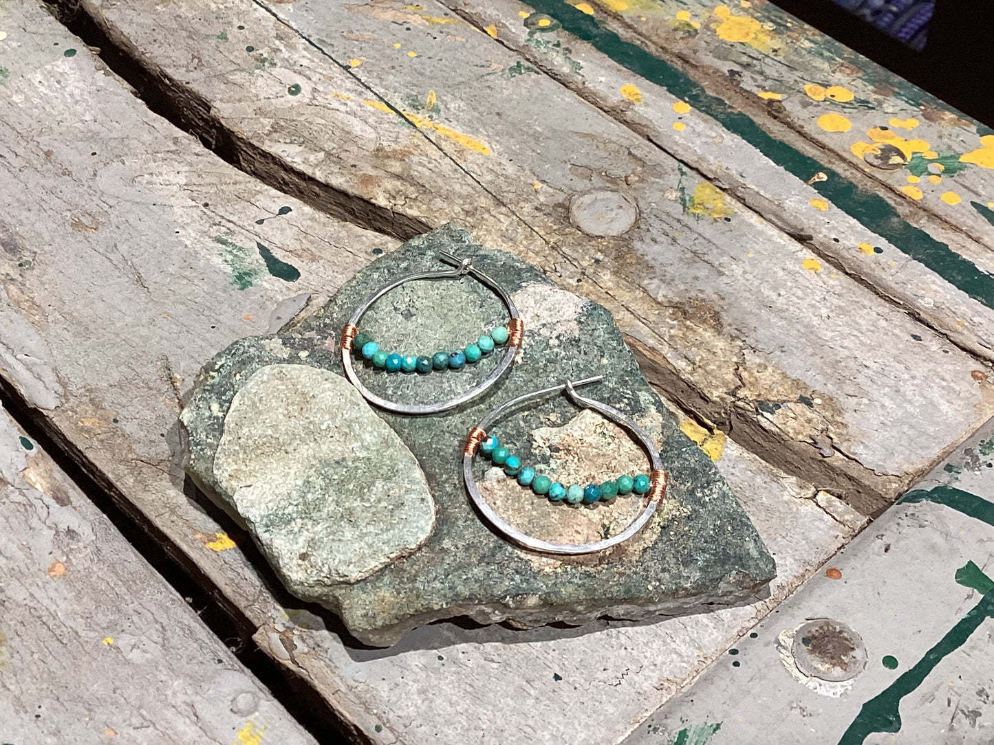 Hoop earrings with turquoise beads on a stone surface