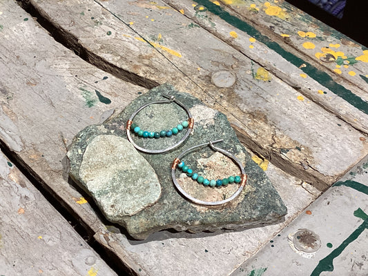 Hoop earrings with turquoise beads on a stone surface