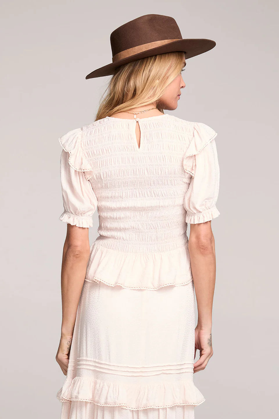 Woman wearing a white dress and brown hat on a gray background