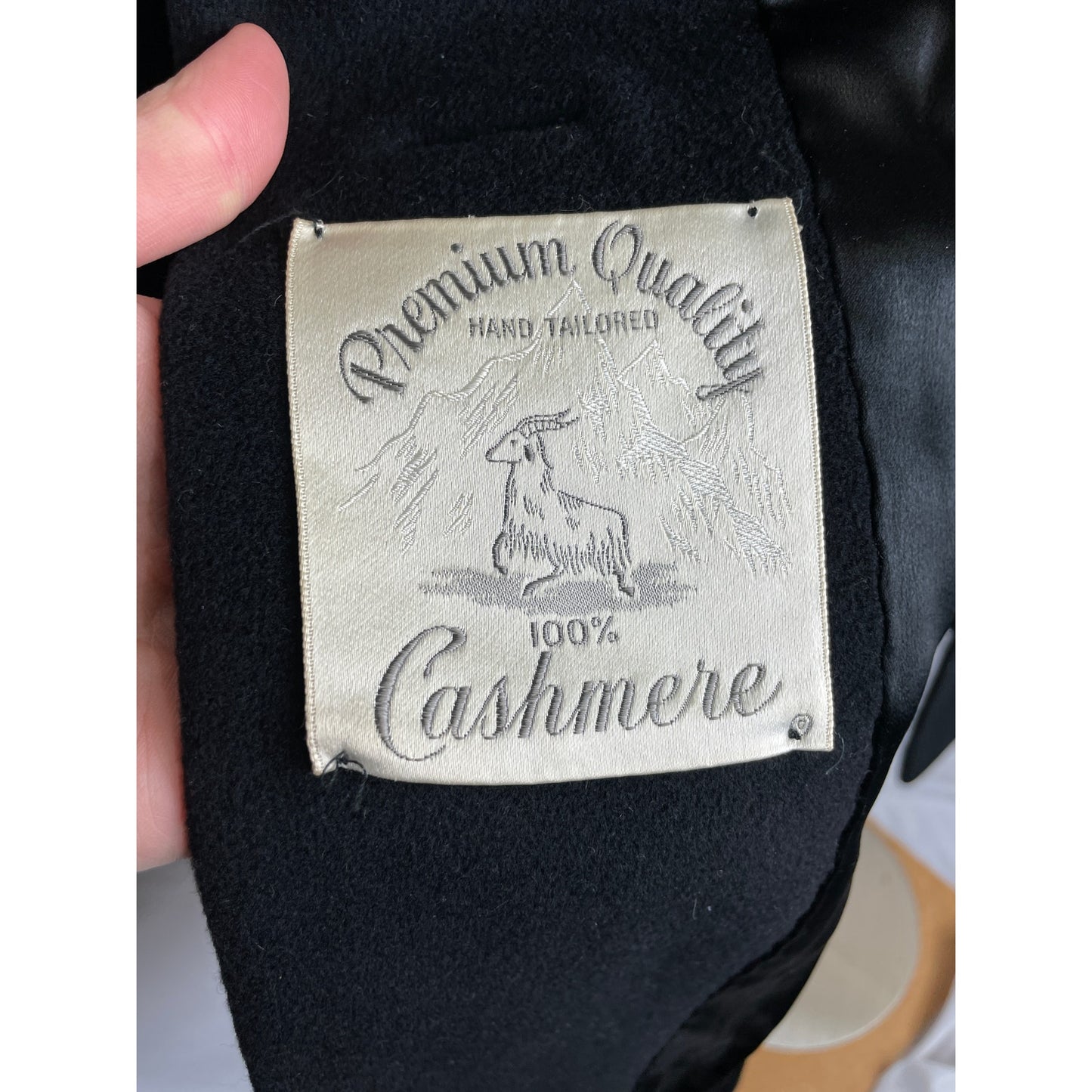 Label on black cashmere fabric indicating 'Premium Quality' and '100% Cashmere'.