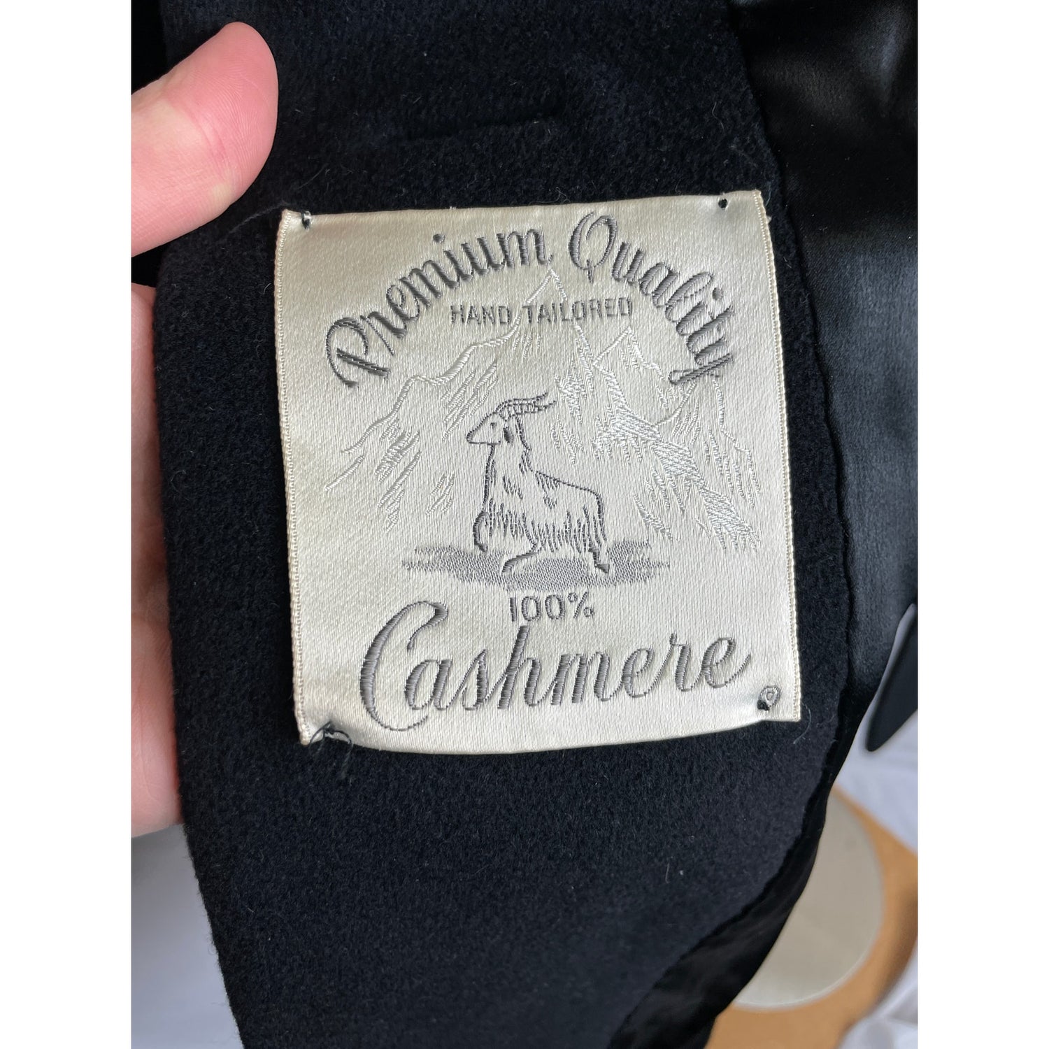 Label on black cashmere fabric indicating 'Premium Quality' and '100% Cashmere'.