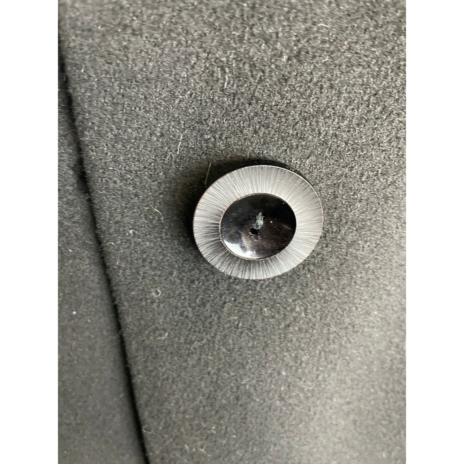 Metallic button on a textured gray fabric background