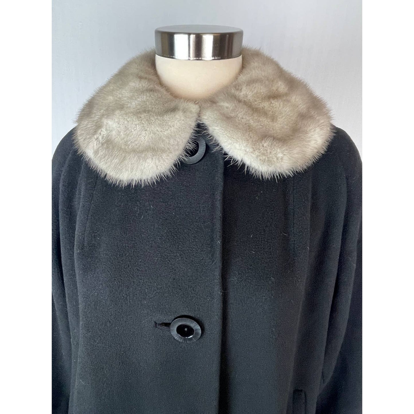 Dark coat with fur collar on a mannequin against a light background