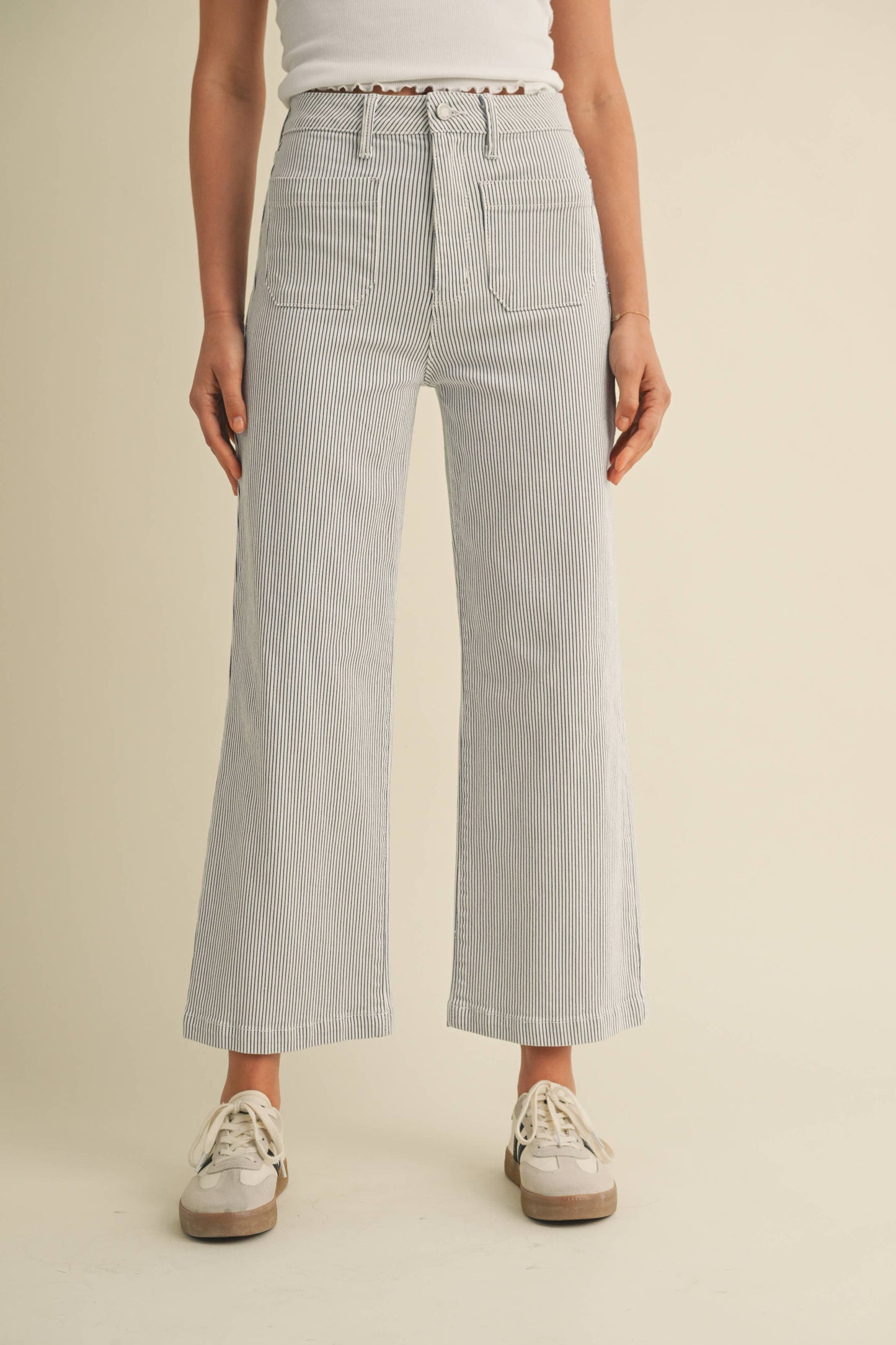 Person wearing light gray striped pants on a beige background