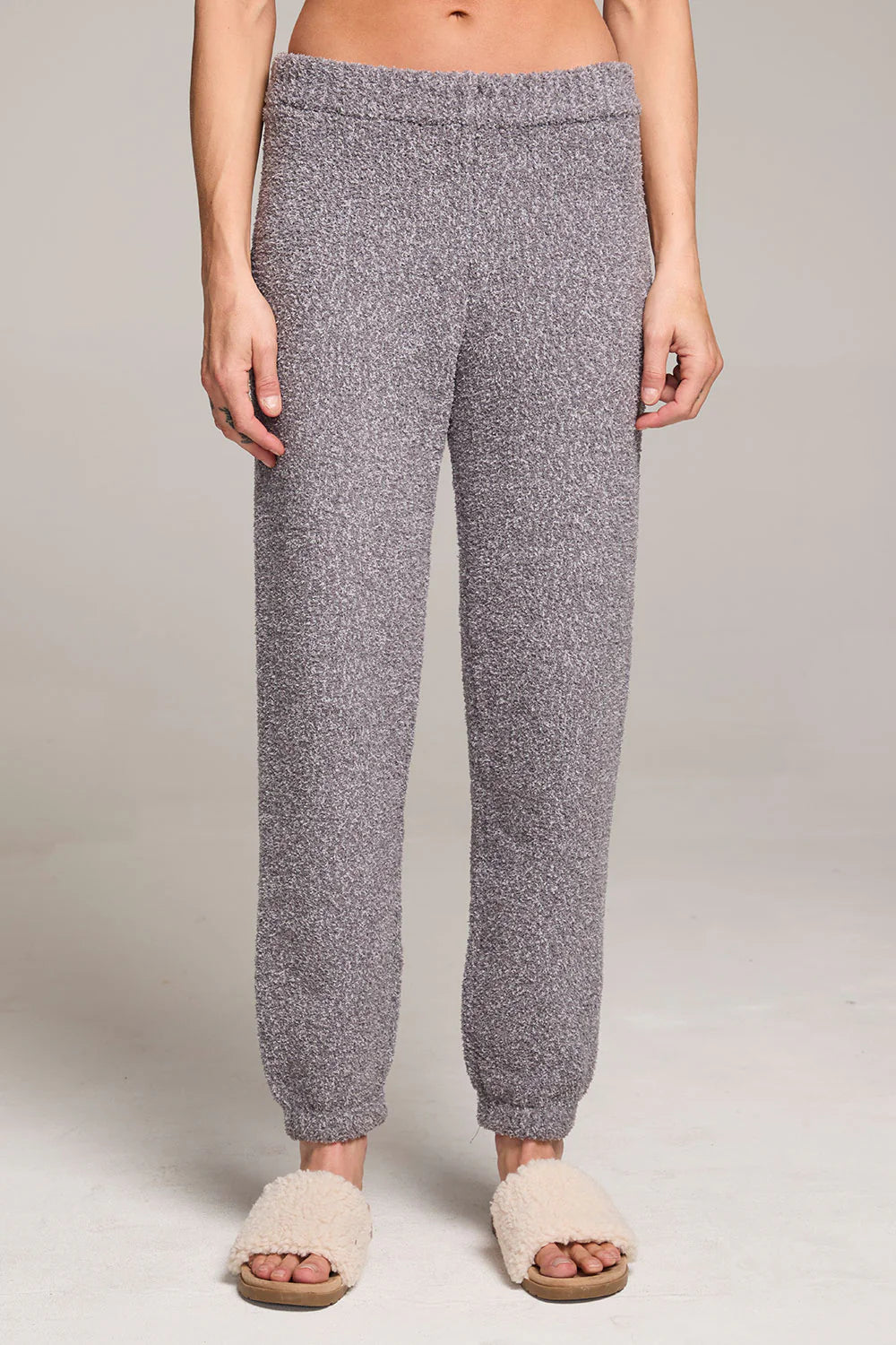 Person wearing gray knitted jogger pants on a plain background