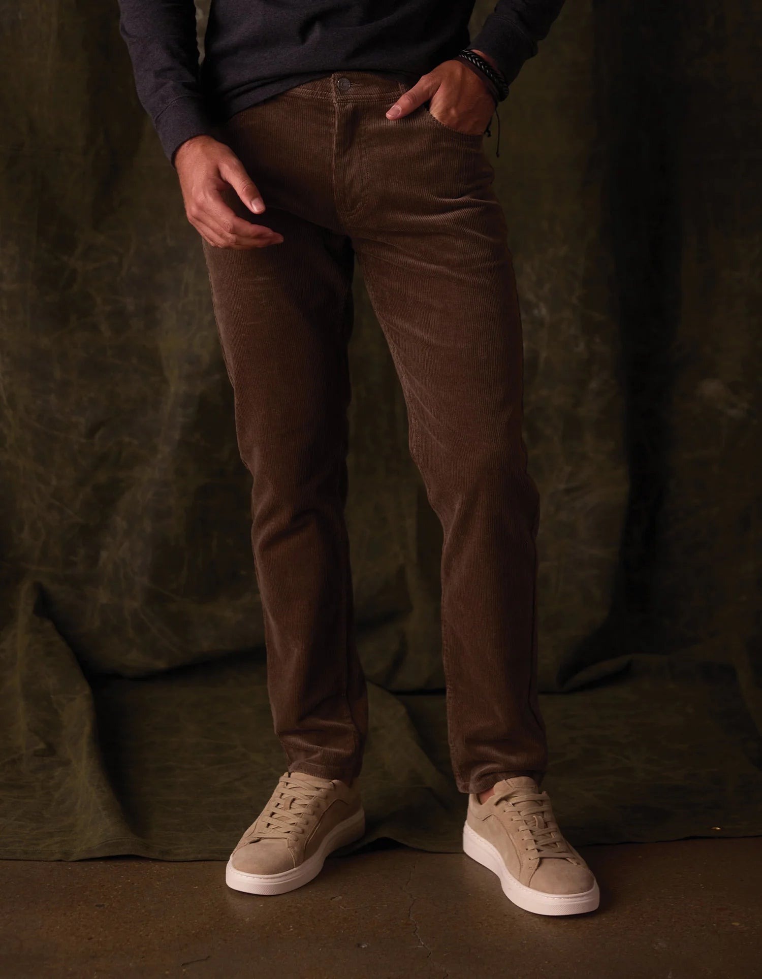 Person wearing brown pants and beige shoes against a dark background