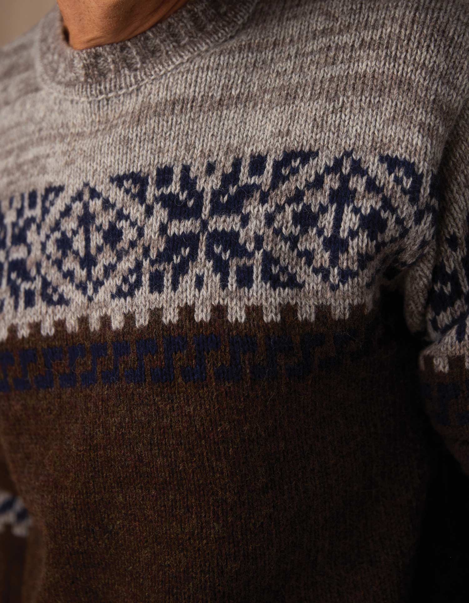 Close-up of a sweater with a patterned design on a neutral background
