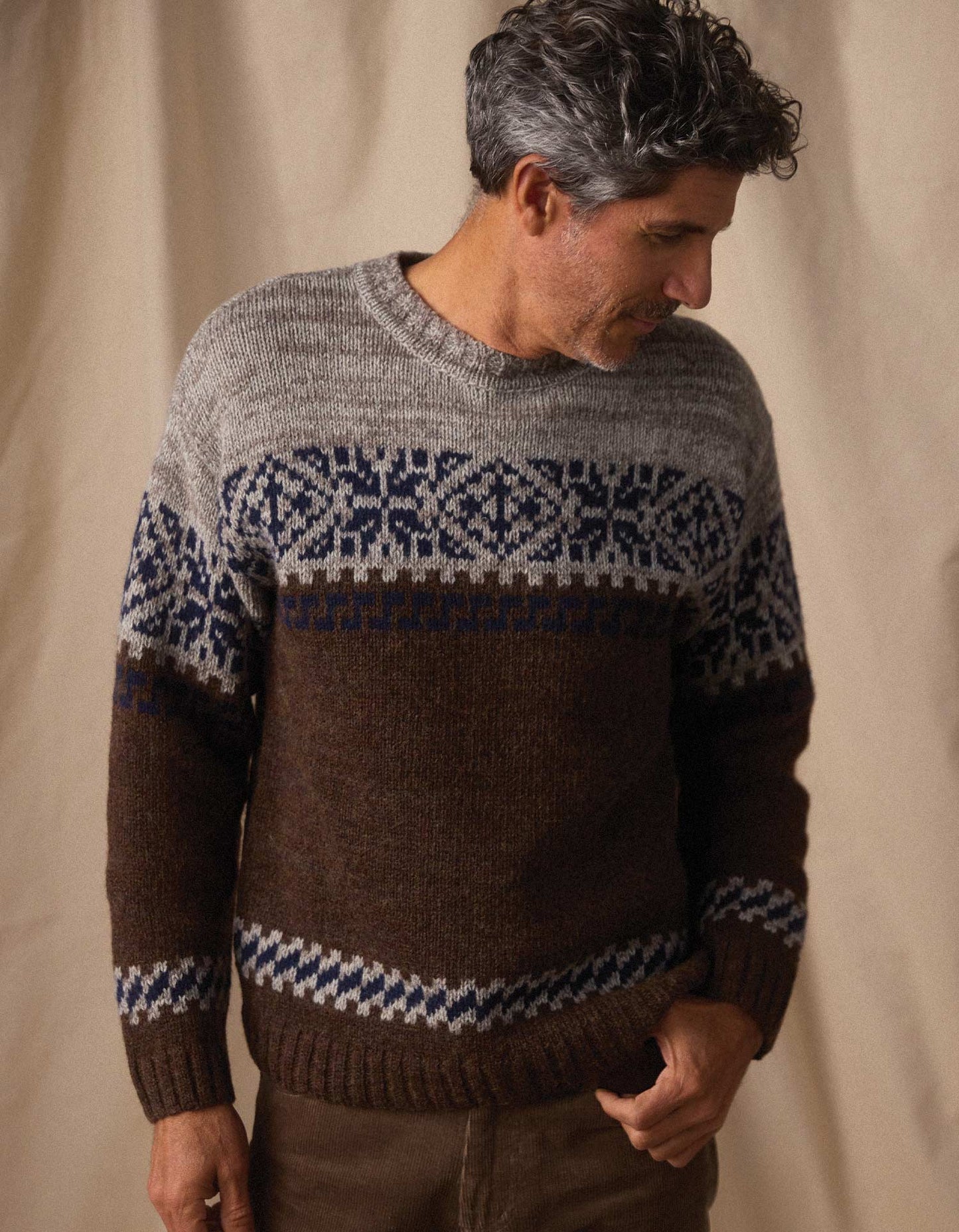 Man wearing a patterned sweater against a beige background