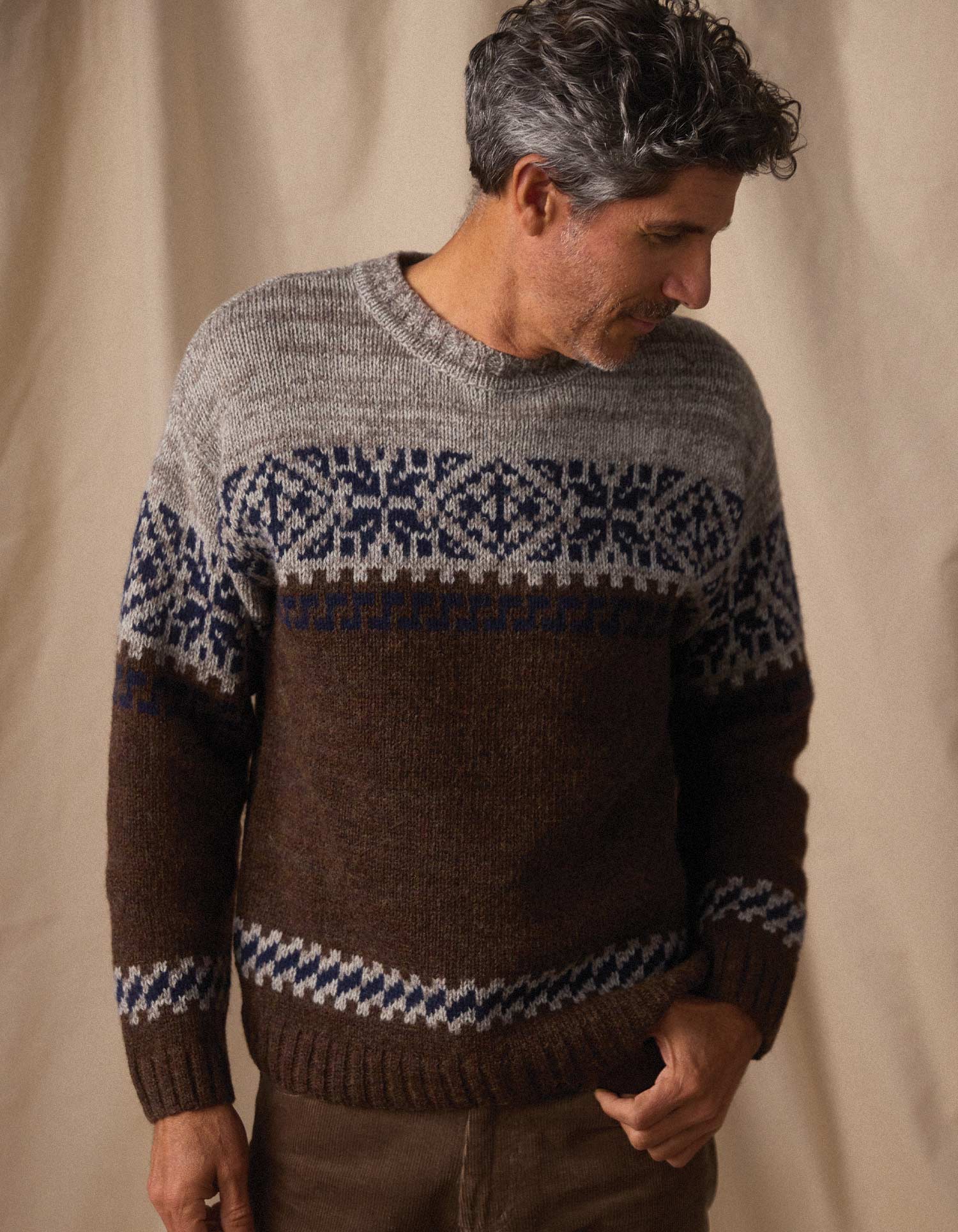 Man wearing a patterned sweater against a beige background