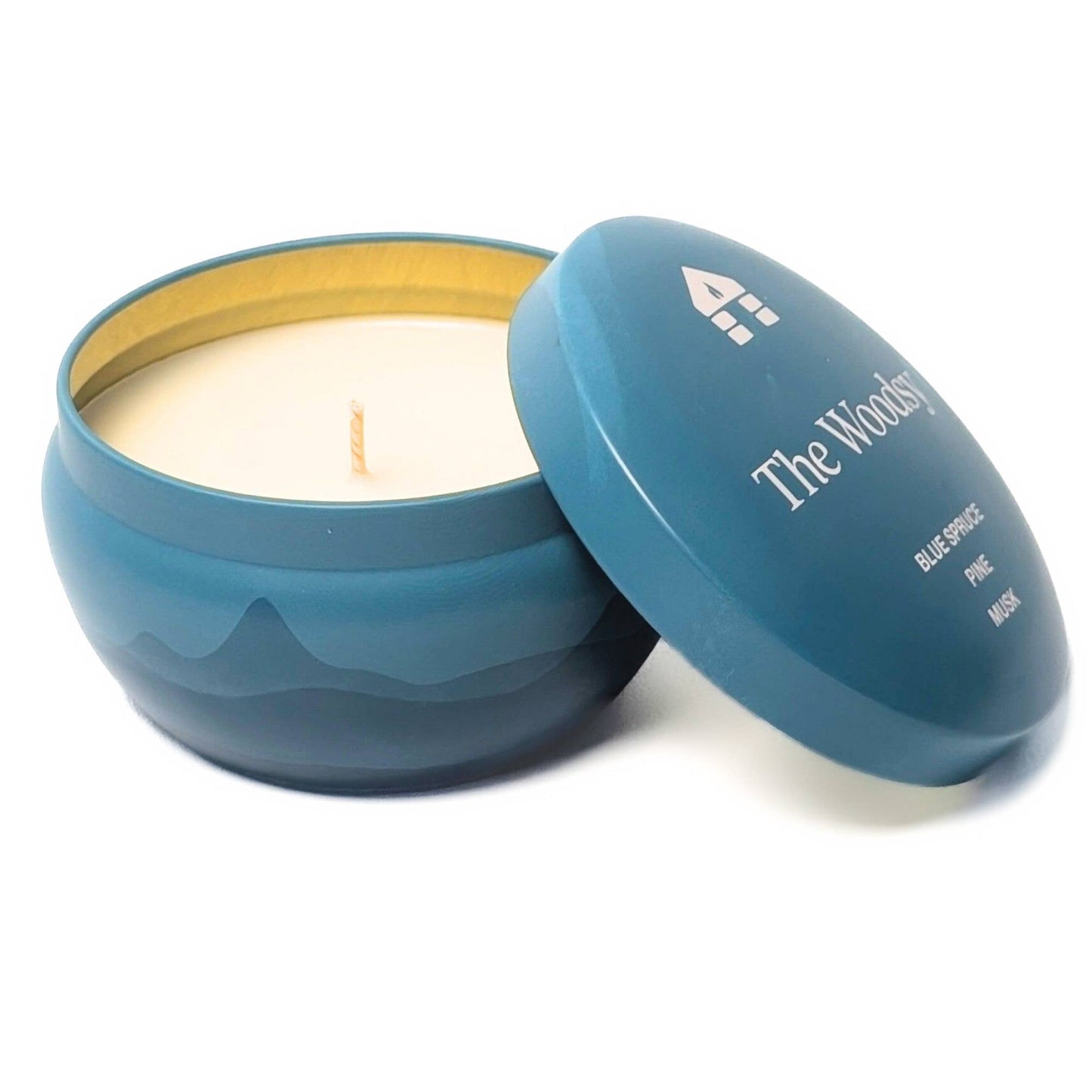 Blue candle in a tin with 'The Woodsy' branding on a white background