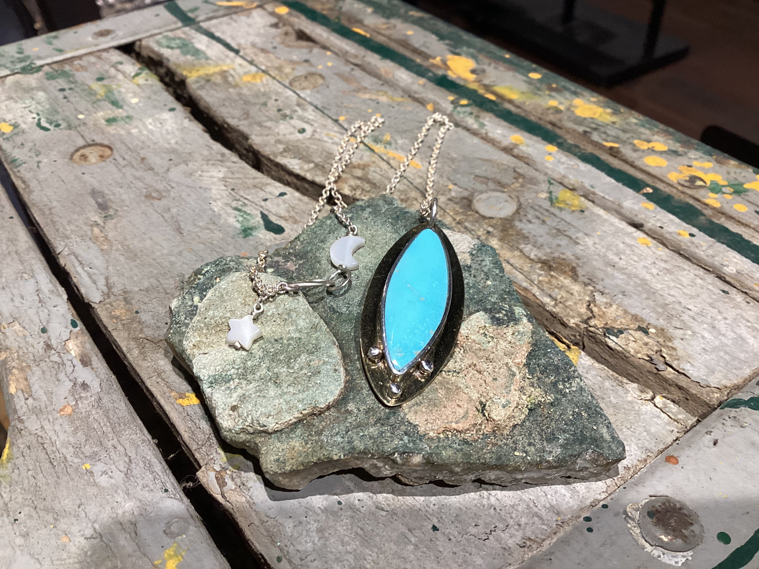 Turquoise pendant necklace on a stone surface with a rustic background