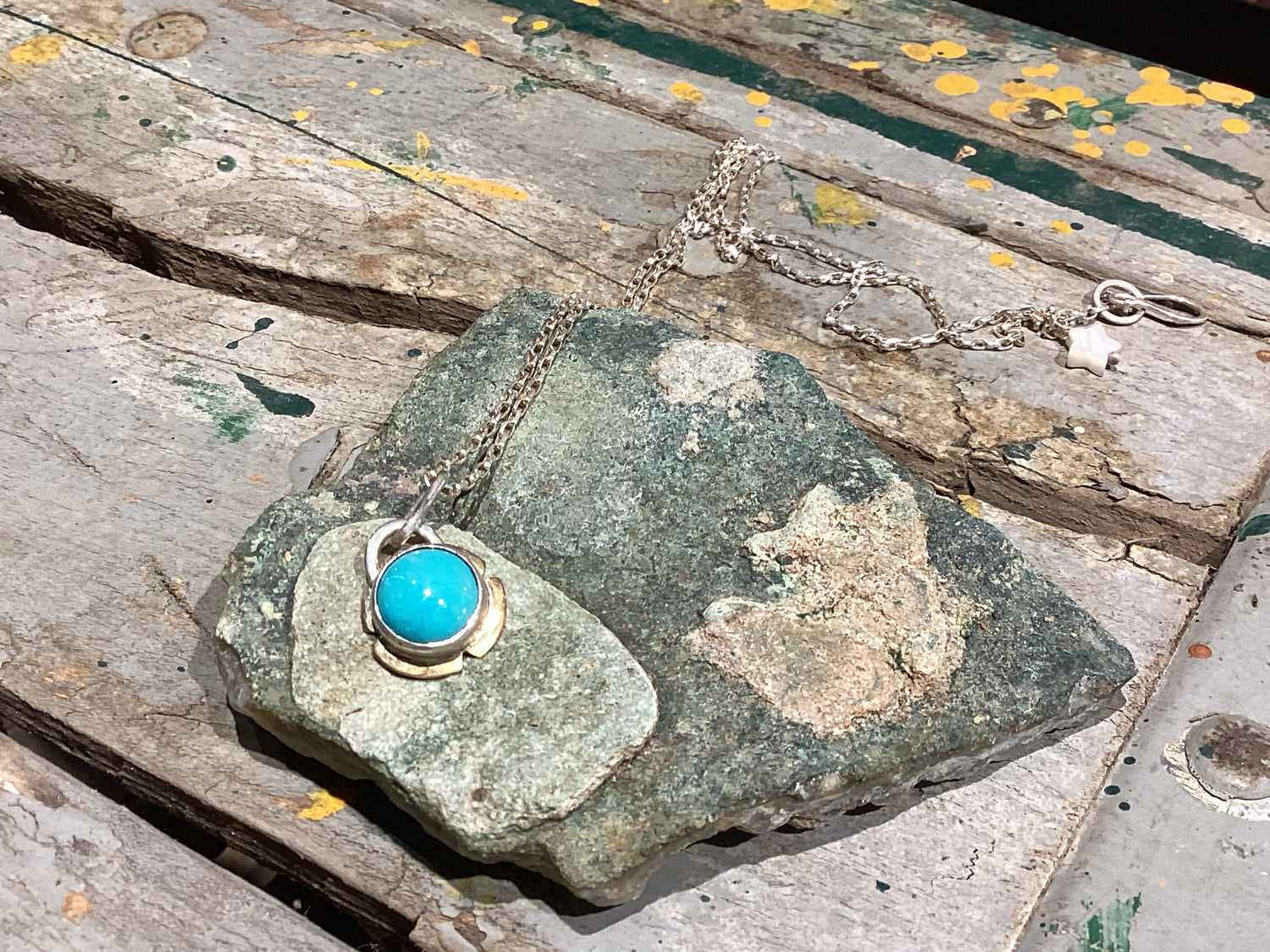 Necklace with turquoise pendant on a stone surface