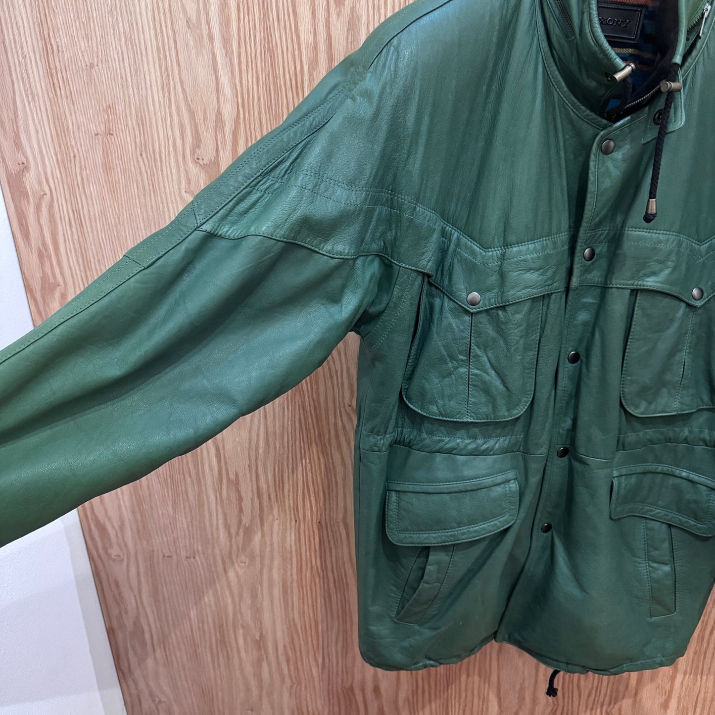 Green jacket with multiple pockets on a wooden floor