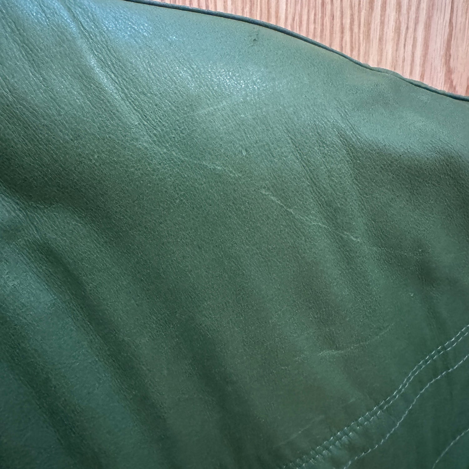 Close-up of a green fabric surface with visible texture and stitching.