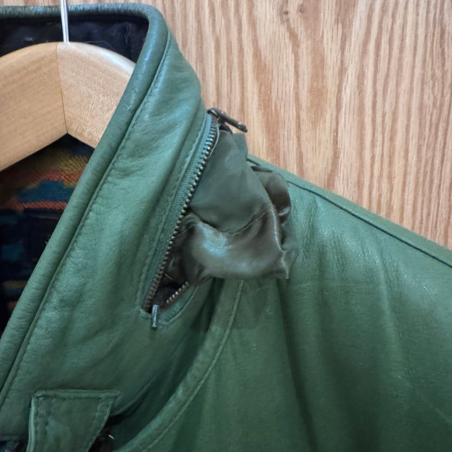 Green jacket on a wooden hanger against a wooden background