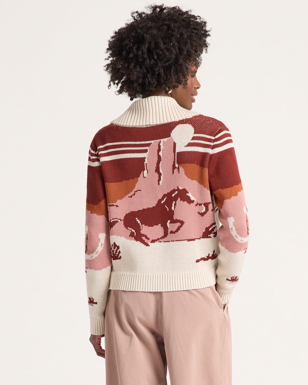 Person wearing a sweater with horse pattern on a plain background