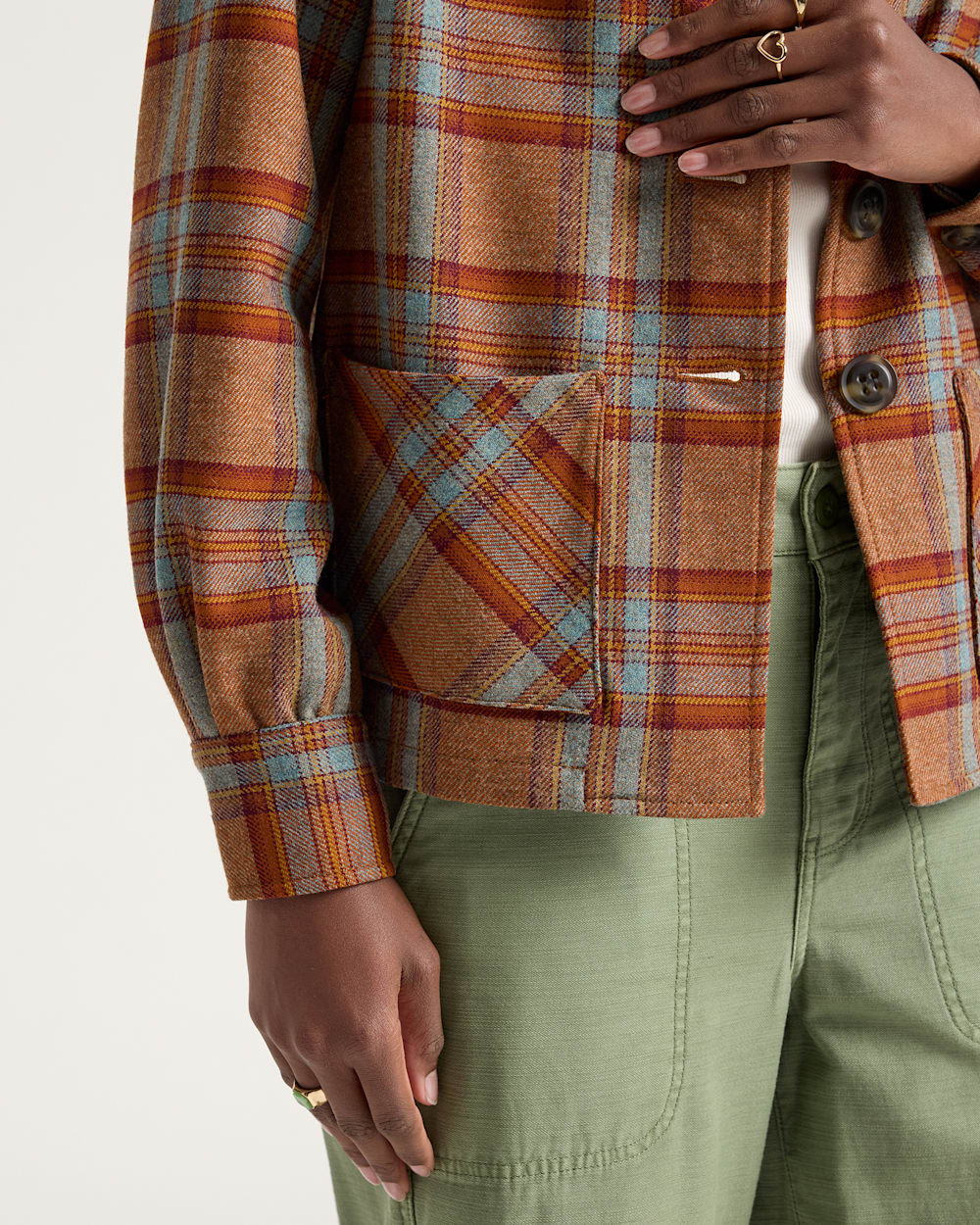 Person wearing a plaid jacket with a neutral background